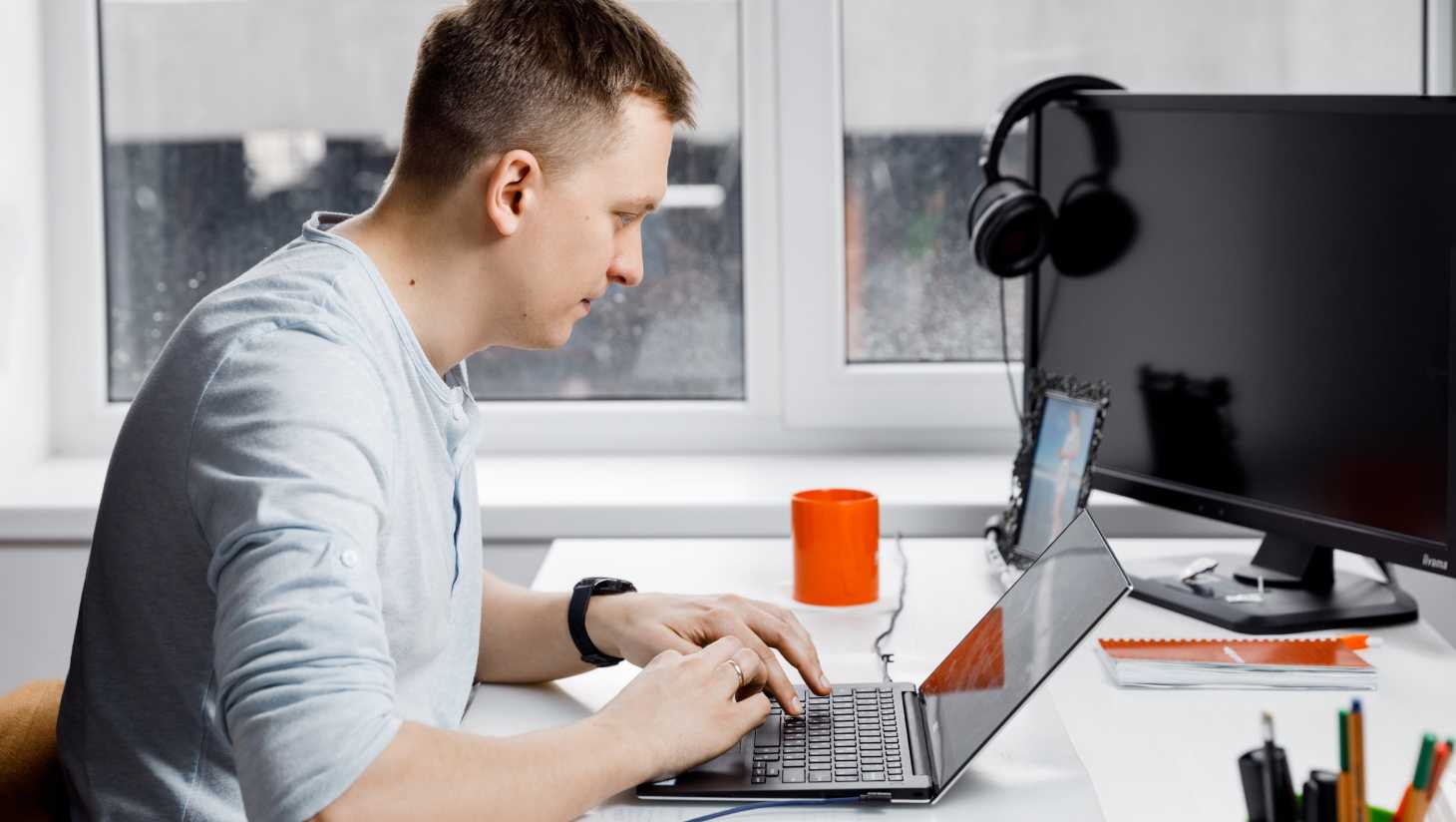 Man in grey shirt behind a computer